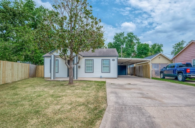 view of front of home with a carport, fence, a front yard, and driveway