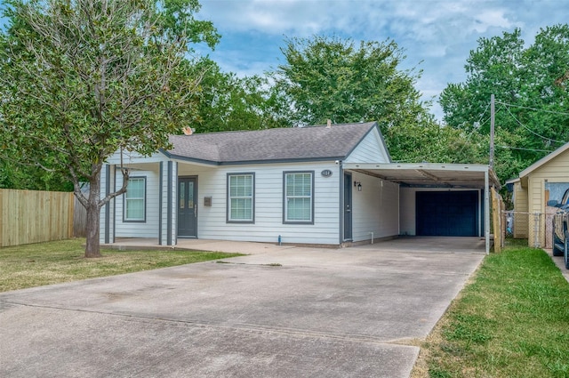 view of front of property with a front lawn, fence, roof with shingles, concrete driveway, and an attached carport