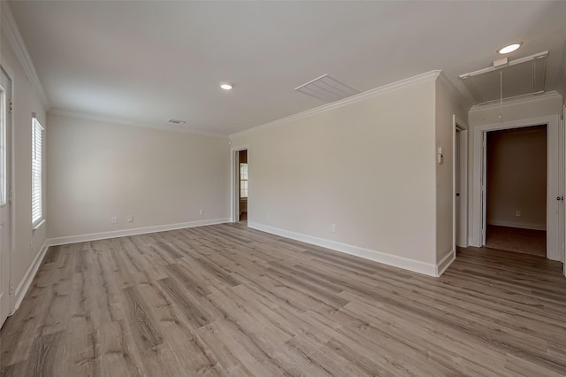 spare room featuring baseboards, attic access, crown molding, and light wood-style floors