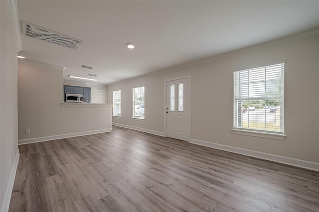 entrance foyer featuring visible vents, ornamental molding, baseboards, and wood finished floors