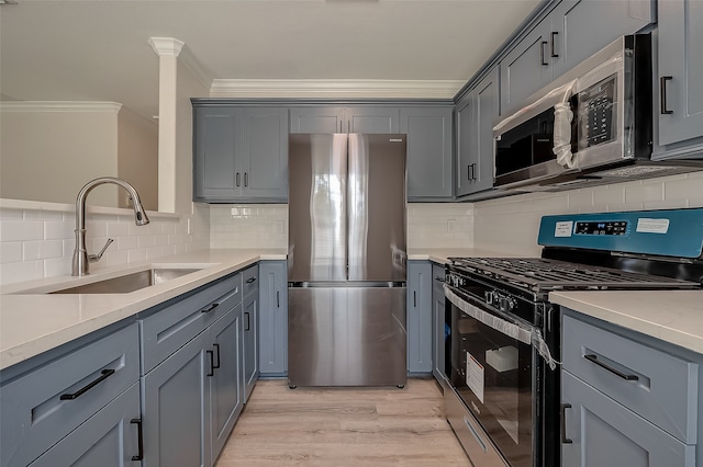 kitchen with appliances with stainless steel finishes, backsplash, sink, crown molding, and light wood-type flooring