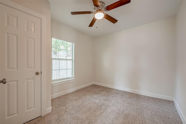 carpeted empty room with a ceiling fan and baseboards