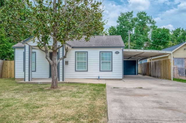 view of front of house featuring an attached carport, a front lawn, fence, concrete driveway, and roof with shingles