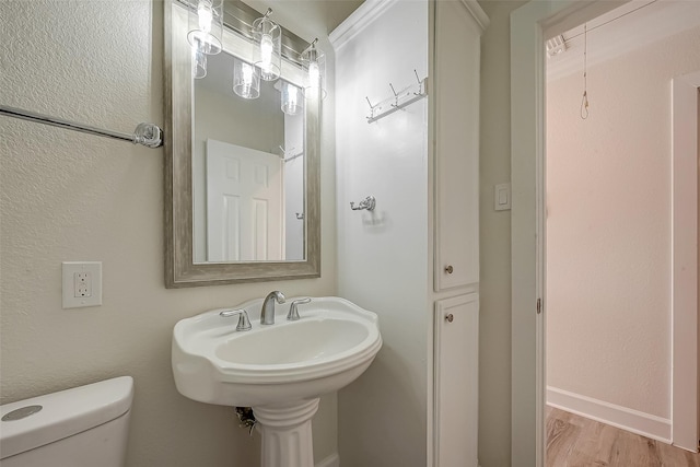 bathroom with toilet, baseboards, and wood finished floors