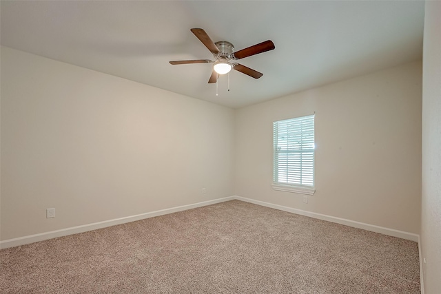 carpeted spare room with ceiling fan and baseboards