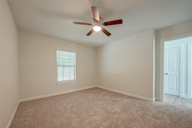 unfurnished room featuring baseboards, light carpet, and a ceiling fan