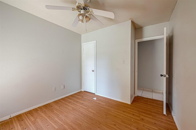 unfurnished bedroom featuring light wood finished floors, a ceiling fan, and baseboards