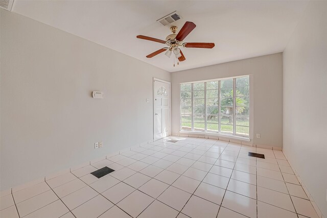 tiled empty room featuring visible vents and a ceiling fan