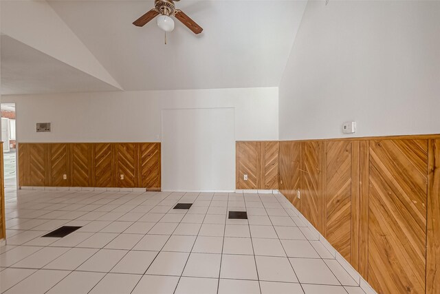 unfurnished room with a wainscoted wall, wood walls, and vaulted ceiling