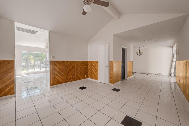 empty room featuring a wainscoted wall, ceiling fan with notable chandelier, visible vents, and wooden walls