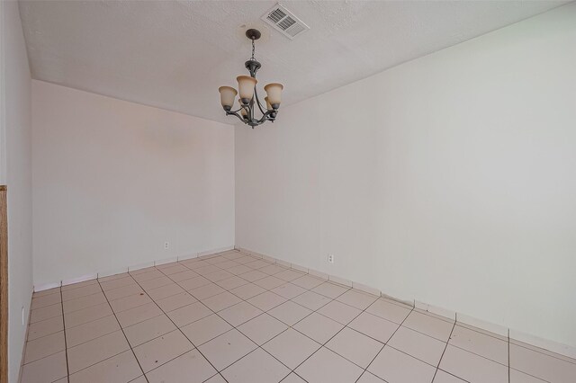 unfurnished room featuring an inviting chandelier, light tile patterned floors, and visible vents