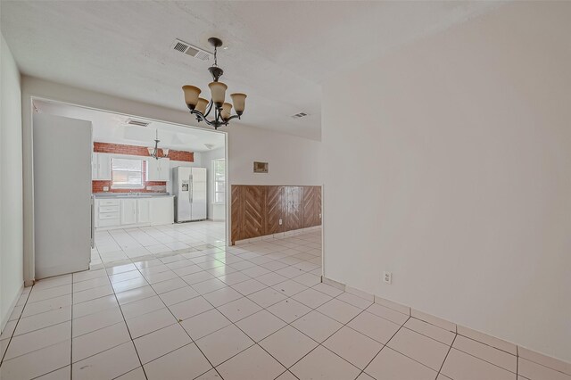 spare room with a chandelier, light tile patterned floors, and visible vents