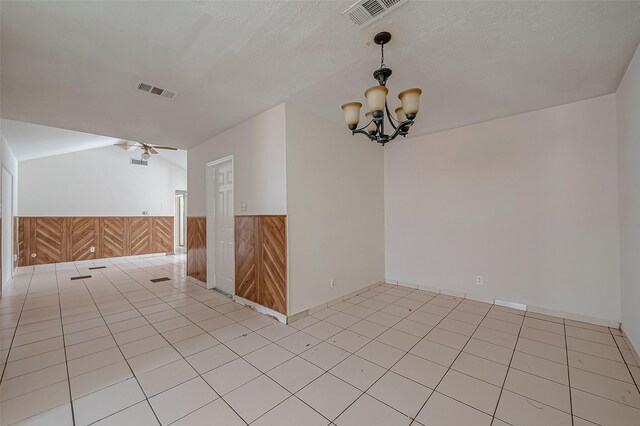 spare room featuring a wainscoted wall, a textured ceiling, visible vents, and wooden walls