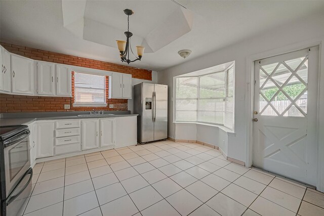 kitchen with a sink, white cabinets, appliances with stainless steel finishes, dark countertops, and a raised ceiling