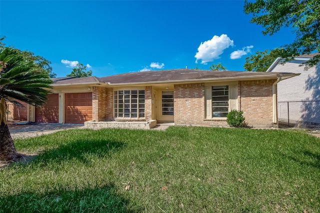 back of house with an attached garage, brick siding, fence, and a yard