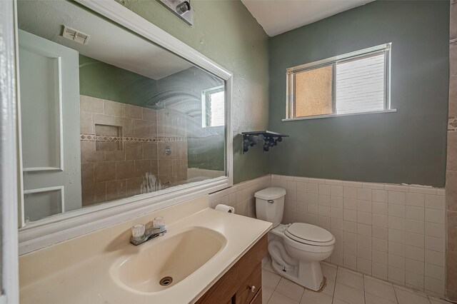 full bath featuring visible vents, wainscoting, toilet, tile patterned floors, and a tile shower