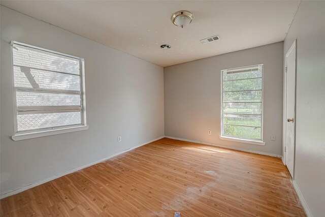 spare room featuring light wood-style flooring, visible vents, and baseboards