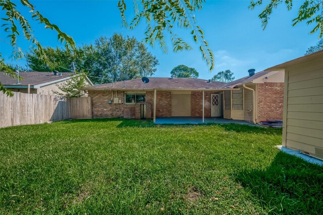 back of property with a yard, a patio area, fence, and brick siding