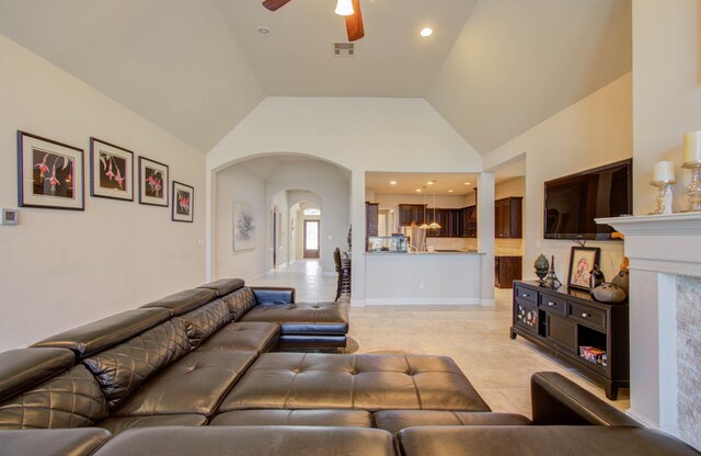 tiled living room with ceiling fan and high vaulted ceiling