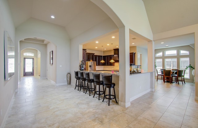 kitchen featuring backsplash, light tile patterned floors, custom exhaust hood, light stone counters, and stainless steel fridge with ice dispenser