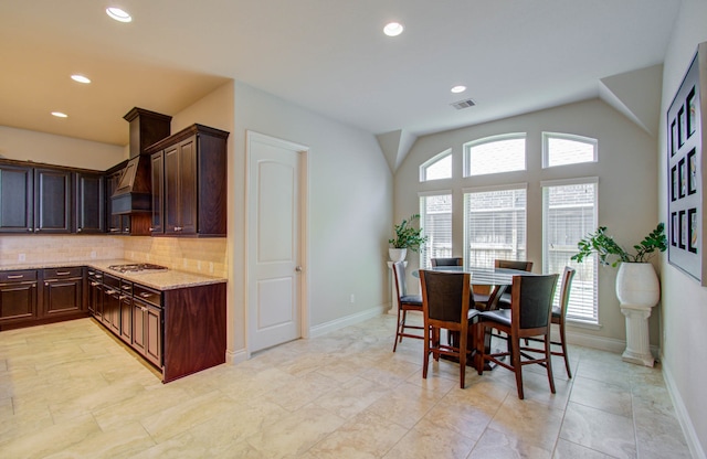 kitchen featuring a wealth of natural light, backsplash, and lofted ceiling