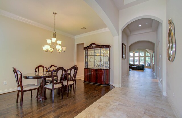 dining area with hardwood / wood-style floors, crown molding, and a chandelier