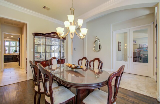 dining area featuring ornamental molding, an inviting chandelier, and hardwood / wood-style flooring