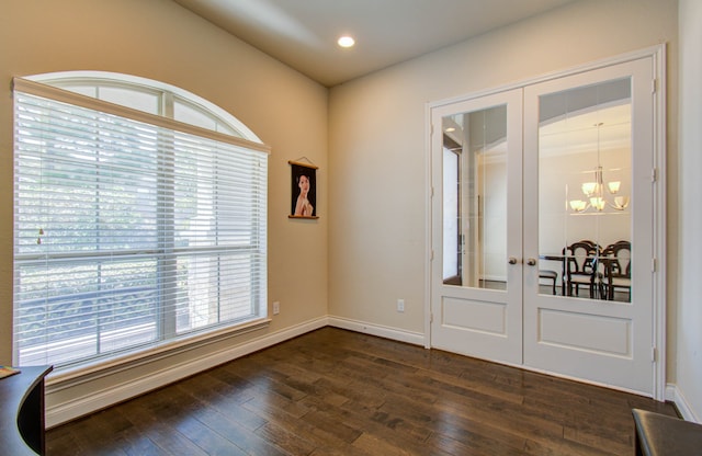 empty room featuring french doors, dark hardwood / wood-style flooring, and a chandelier