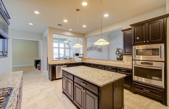 kitchen featuring appliances with stainless steel finishes, kitchen peninsula, a kitchen island, ceiling fan, and hanging light fixtures