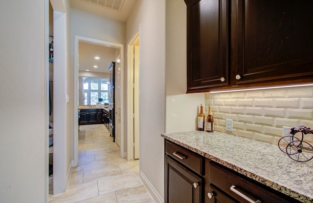 kitchen featuring light tile patterned flooring, backsplash, and dark brown cabinets