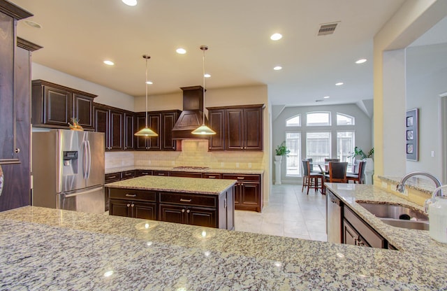 kitchen with custom range hood, light stone counters, light tile patterned floors, lofted ceiling, and stainless steel appliances