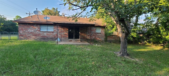 rear view of house featuring a patio, fence, a lawn, and brick siding