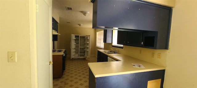 kitchen with range with electric cooktop, visible vents, dark cabinets, light countertops, and a sink