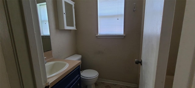 bathroom featuring toilet, a healthy amount of sunlight, baseboards, and vanity