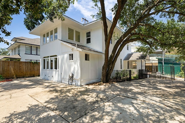 rear view of house featuring fence and concrete driveway