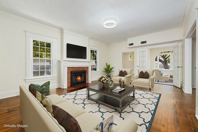 living room featuring ornamental molding, a brick fireplace, a textured ceiling, and dark hardwood / wood-style flooring