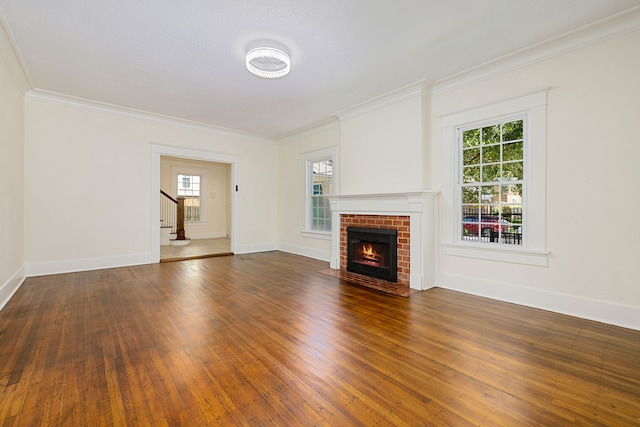 unfurnished living room with baseboards, a brick fireplace, ornamental molding, stairs, and wood-type flooring