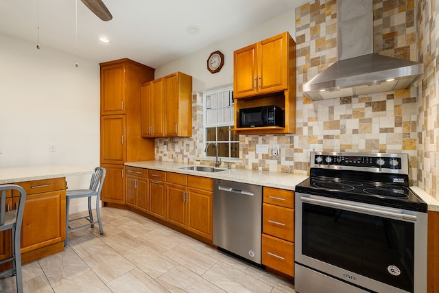 kitchen with brown cabinets, a sink, wall chimney range hood, and stainless steel appliances