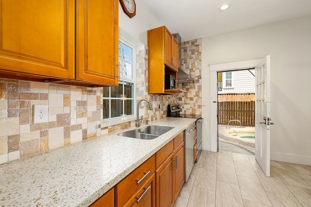 kitchen with light stone countertops, plenty of natural light, tasteful backsplash, and sink