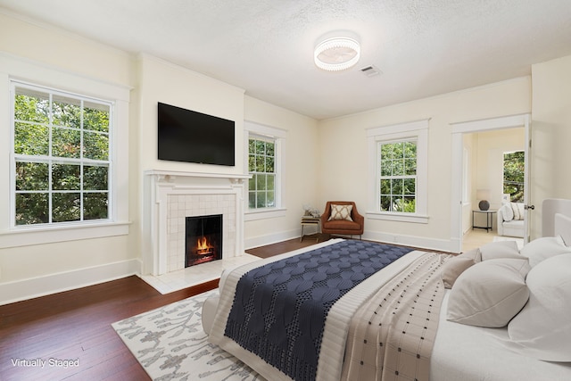 bedroom with a textured ceiling, a fireplace, and hardwood / wood-style floors