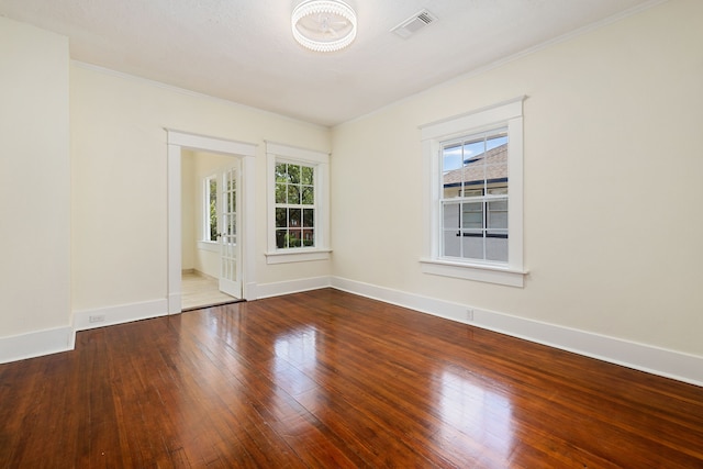 unfurnished room featuring visible vents, baseboards, plenty of natural light, and hardwood / wood-style flooring