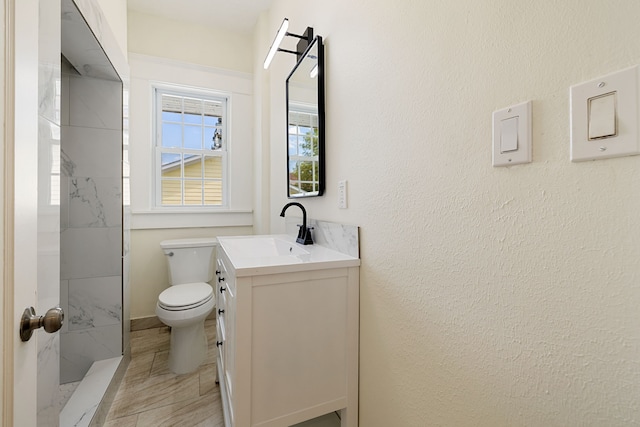 bathroom featuring tiled shower, vanity, and toilet