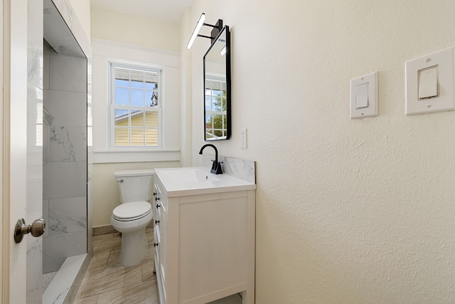 bathroom featuring toilet, vanity, and a marble finish shower