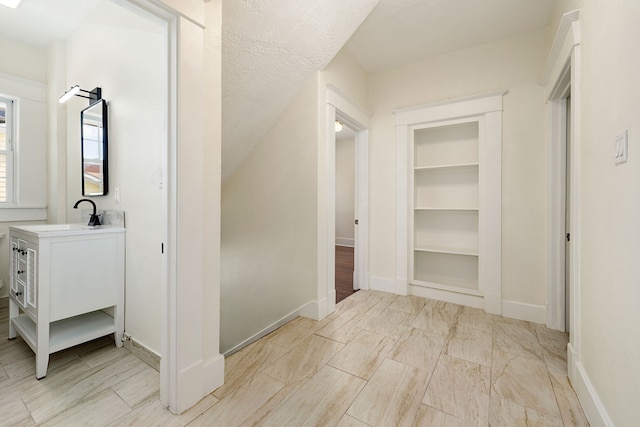 corridor with baseboards and a sink