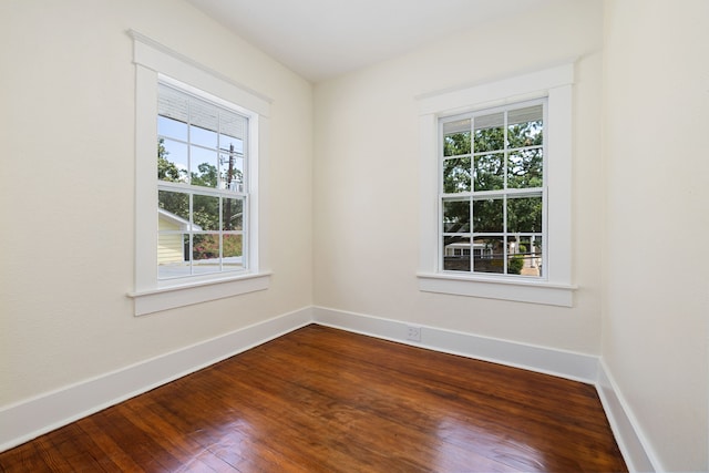 empty room with dark wood-type flooring, baseboards, and a healthy amount of sunlight