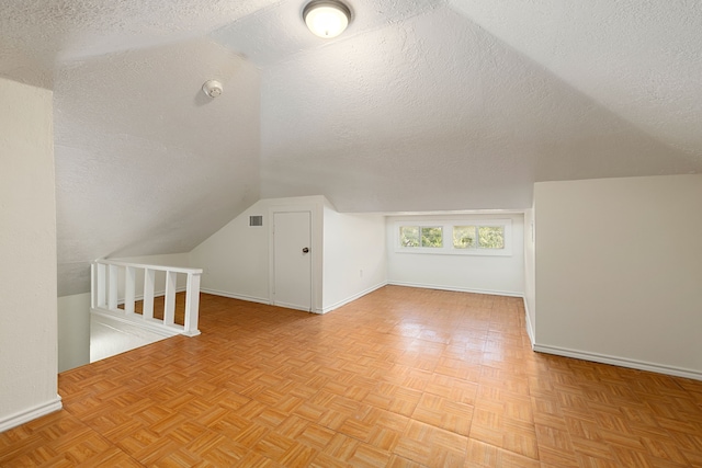 bonus room with visible vents, baseboards, vaulted ceiling, and a textured ceiling