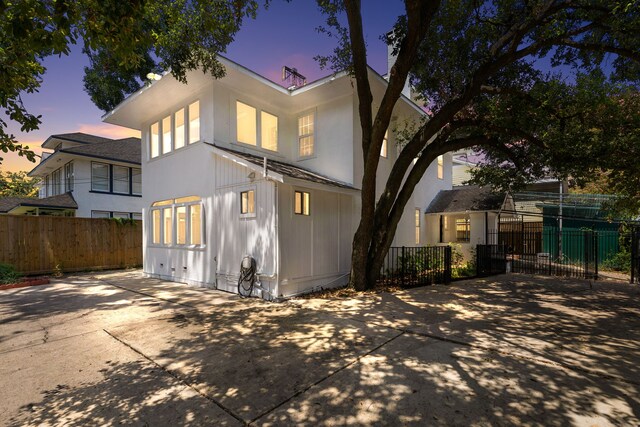 rear view of property featuring fence and concrete driveway