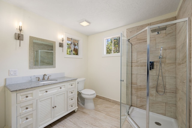 full bathroom with baseboards, toilet, a textured ceiling, a shower stall, and vanity