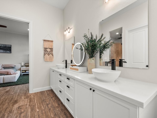 full bath with double vanity, wood finished floors, a sink, and baseboards