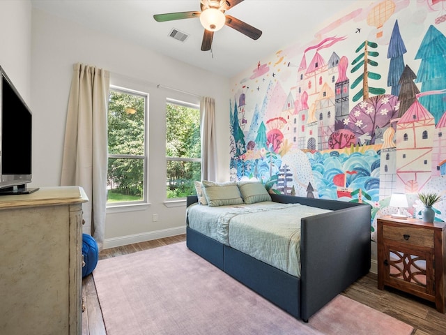 bedroom with ceiling fan, wood finished floors, visible vents, and baseboards